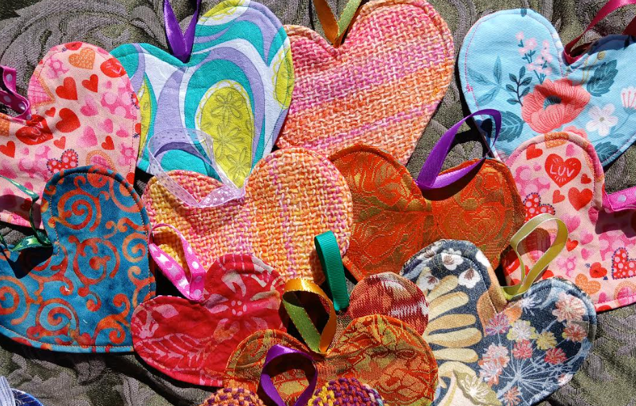 A selection of brightly coloured fabric hearts laid flat on a bit of green fabric